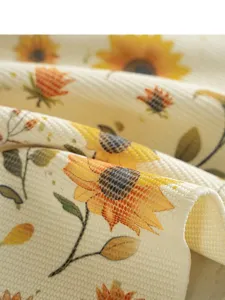 Nahaufnahme eines gewebten Stoff-Tischläufers mit Sonnenblumen-Print und feiner Textur.