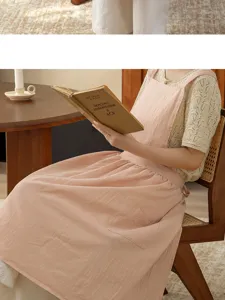 Detail shot of a soft pink cotton apron with convenient pocket and comfortable shoulder straps.