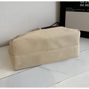 Detailed view of the beige canvas tote bag, showing reinforced bottom stitching and fabric.