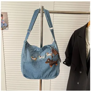 Detail view of casual denim shoulder bag featuring cute dog embroidery and stylish dachshund pendant.