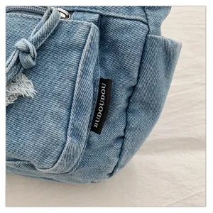 Primer plano detallado de bolso de hombro de lona vaquera con bolsillo frontal y cordón.