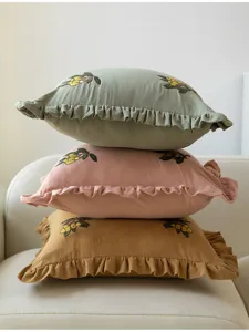 Detail view of decorative embroidered throw pillow featuring lovely fruit motif and ruffled edge.