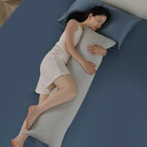 Detailed shot of a long body pillow with grid texture, used for side sleeping comfort.