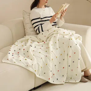 Nordic minimalist knit throw blanket with colorful pom poms for cozy sofa and spring home.