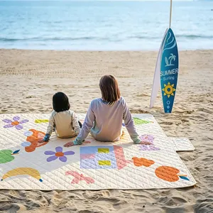 Outdoor waterproof picnic mat detail showing cute cartoon patterns on sandy beach setting.