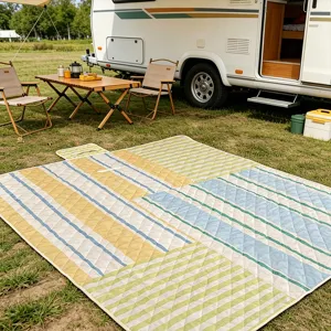 Detailed view of outdoor waterproof picnic mat with colorful striped pattern on green grass.