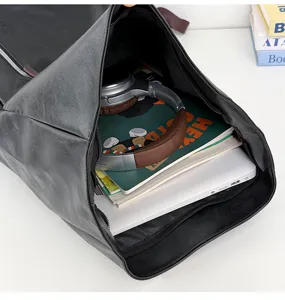 Detail view of a black roll-top backpack showing large capacity interior with laptop and books.