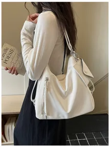 Detail view of white slouchy leather tote bag showing multi-functional straps and small pouch.