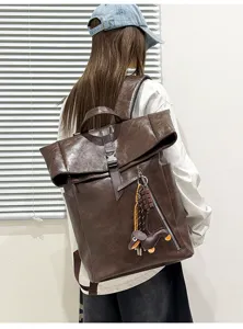 Detail view of the dark brown roll-top backpack, showing texture and large capacity.
