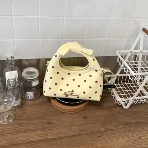 Dettaglio della borsa a mano gialla a pois con manico a fiocco, perfetta per outfit primaverili.