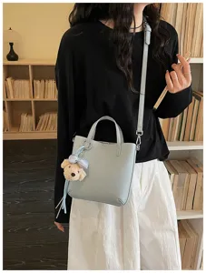 Light blue leather tote bag detail with cute bear pendant and crossbody strap.