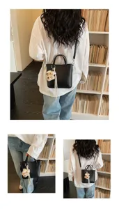 Chic black leather shoulder bag for women, featuring a cute bear plush pendant and casual design.