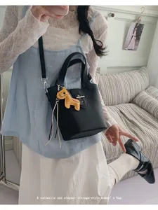 Zwarte lederen emmertas detail met schattige paardenbedel, veelzijdige vintage schoudertas stijl.