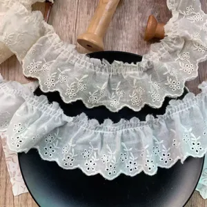 Close-up detail view of white ruffled lace trim with delicate embroidered hollow flowers for DIY crafts.