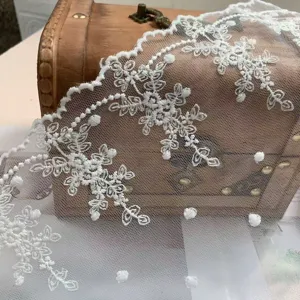 Bande de dentelle blanche avec broderie florale et pois pour déco de robe détail.