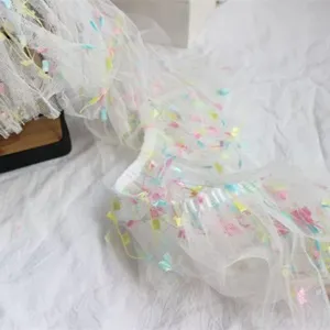 Detail shot of 10cm white mesh lace trim with colorful tassels for garment and curtain decor.