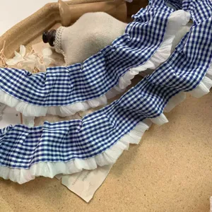 Close-up view of blue and white plaid ruffle lace trim and sheer chiffon for DIY crafts.