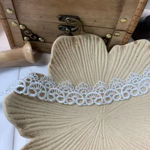 Close-up of white lace trim detail, delicate hollow embroidery for DIY crafts and apparel.