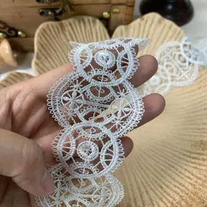 Primo piano del delicato bordo in pizzo bianco con intricati motivi geometrici circolari.