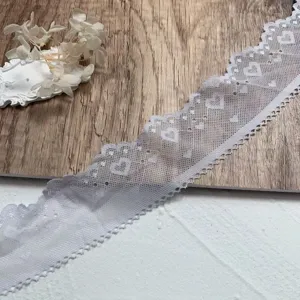 Detailed view of the 5cm wide white lace trim featuring delicate heart embroidery patterns.