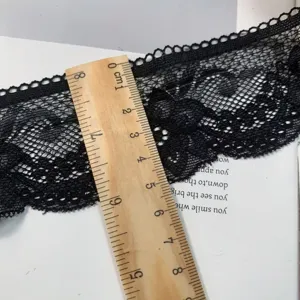 Detailed close-up view of black lace trim measured with a ruler for width and texture.