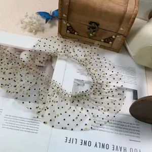 Detailed view of 8cm beige mesh ruffled lace trim with black polka dots and gold foil.