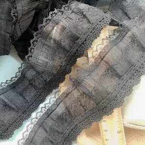 Detail van zwarte geplooide chiffon kantafwerking, ideaal voor DIY kleding en manchetten.