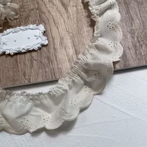 Close-up detail of white embroidered cotton lace trim, delicate hollow design for DIY crafts.
