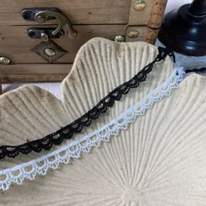 Nahaufnahme von 1cm schwarz-weißer Spitzenborte, ideal für Puppenkleidung und Basteln.
