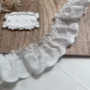 Close-up of white cotton lace trim with hollow embroidery and scalloped edge for DIY sewing.