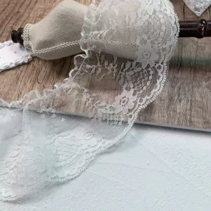 White lace trim detail showing floral embroidery and pleated mesh texture for DIY crafts.