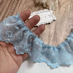 Detalle de ribete de encaje bordado con corazones plisados azul claro, para decoración DIY.