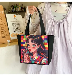 Primer plano detallado del bolso tote de lona negra con estampado de chica anime retro y asas.