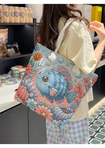 Λεπτομερής λήψη μιας casual κεντημένης τσάντας tote από καμβά με χαριτωμένο μοτίβο ψαριού.