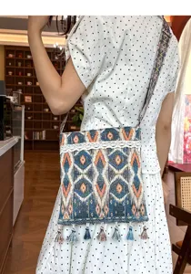 Detalle del bolso cruzado de estilo étnico con borlas y patrón geométrico tejido de calidad.