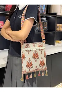 Bolso cruzado tejido de estilo étnico con patrones intrincados y detalles de borlas.