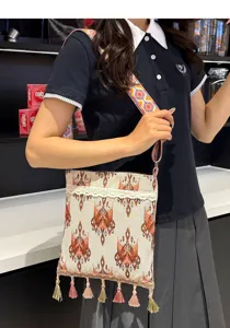 Detalle del bolso cruzado de estilo étnico con borlas colgantes y decoración de encaje.