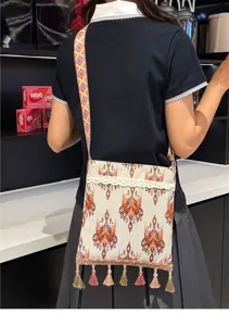 Vista detallada del bolso cruzado tejido de estilo étnico con borlas coloridas, escena de uso casual