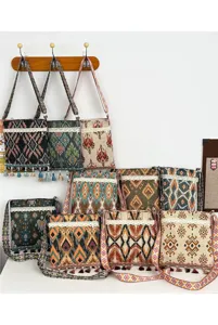 Bolso cruzado tejido de estilo étnico con patrones geométricos, ribete de encaje y borlas delicadas.