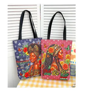 Vue detaillee de grands sacs cabas en toile avec impressions art de femmes noires.