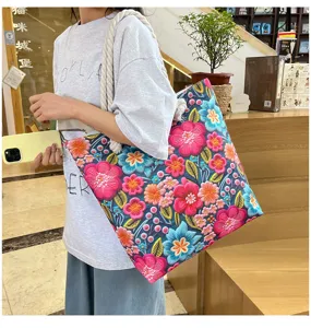 Vista ravvicinata e molto dettagliata di una grande borsa tote in tela ricamata a fiori.