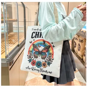 Detalle de bolso de lona con estampado de mariposa y arcoíris colorido y texto inspirador.