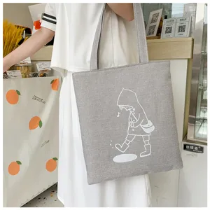 Vista dettagliata della borsa tote in tela grigia con simpatica stampa cartoon e spallaci.