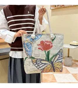 Gedetailleerd overzicht van de geweven canvas tote tas met vlinder- en tulpenborduurwerk.