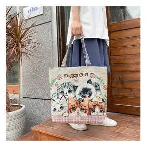 Canvas tote bag detail showing cute woven cat pattern, striped handle and large capacity.