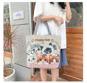 Canvas tote bag featuring cute woven cat designs and comfortable striped straps for daily use.
