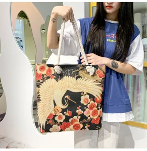Gros plan du sac fourre-tout brodé de style chinois montrant le motif grue et prune dorée.