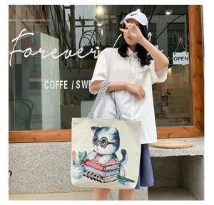 Stylish canvas tote bag featuring a cute cat reading books design with striped handles.