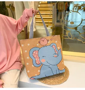 Vista dettagliata della borsa in tela con ricamo di elefante e manici a righe resistenti.