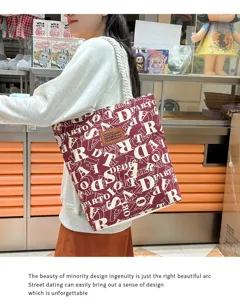 Detailansicht großer Segeltuch Schultertasche in Bordeaux mit weißem Buchstabenmuster für Alltag.